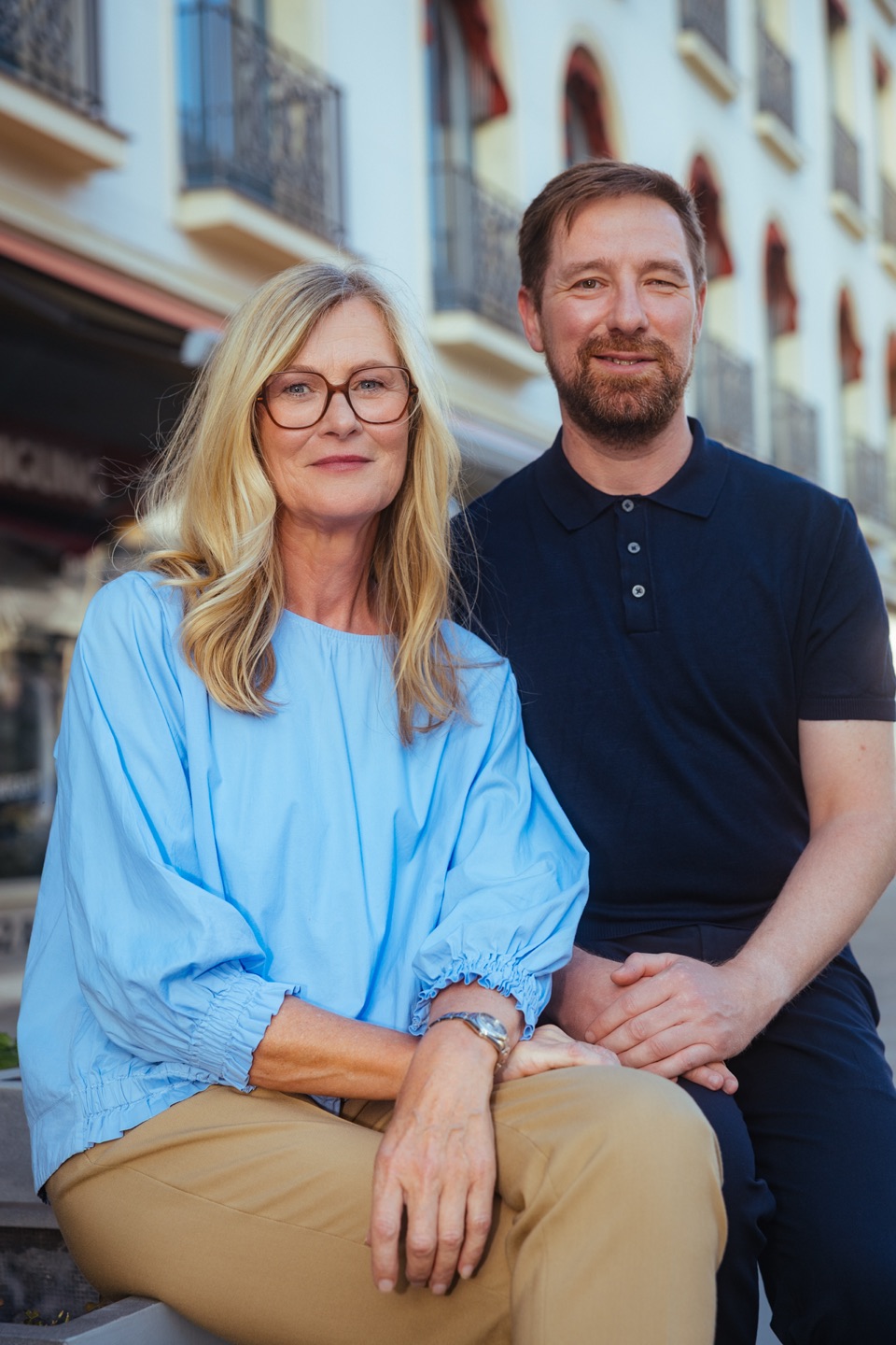 Iris Lanz und Marcel Weber sitzen nebeneinander vor einer Hausfassade. Foto: Michael Geipel, michaelgeipel.de